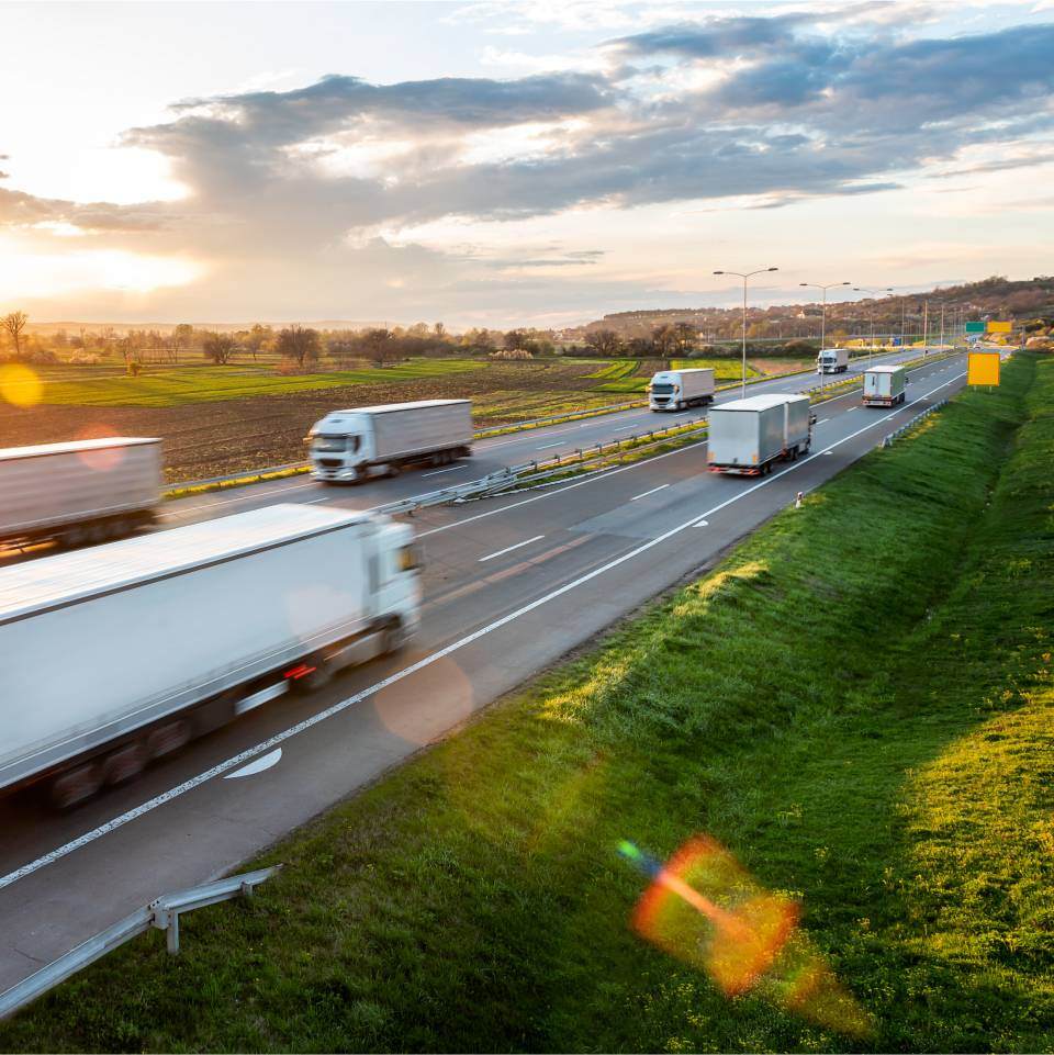 Trucks on motorway with green fields