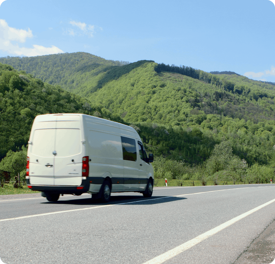 Van driving on road next to hills